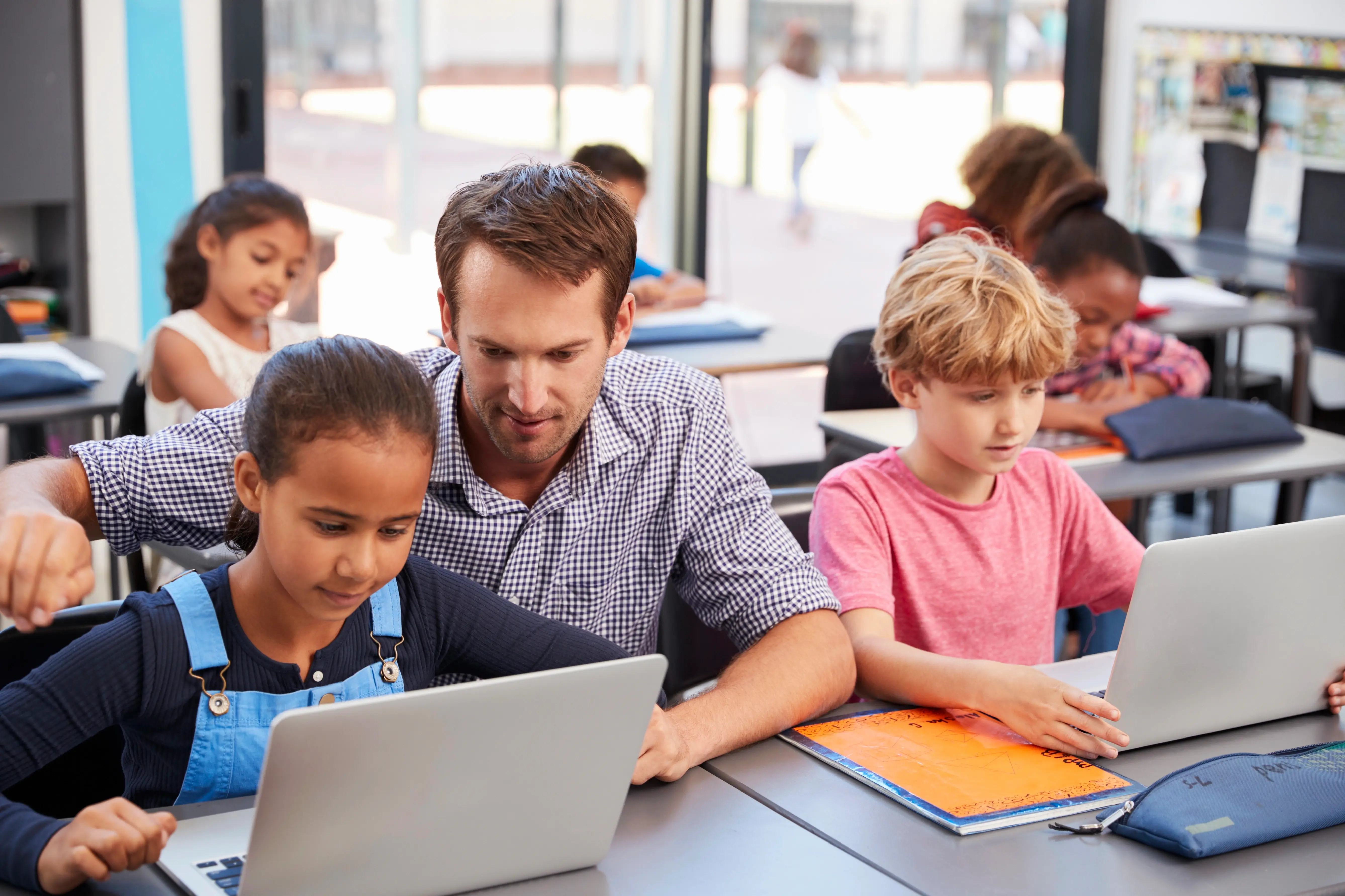 Učitelka ukazuje studentce na monitor během výuky informatiky