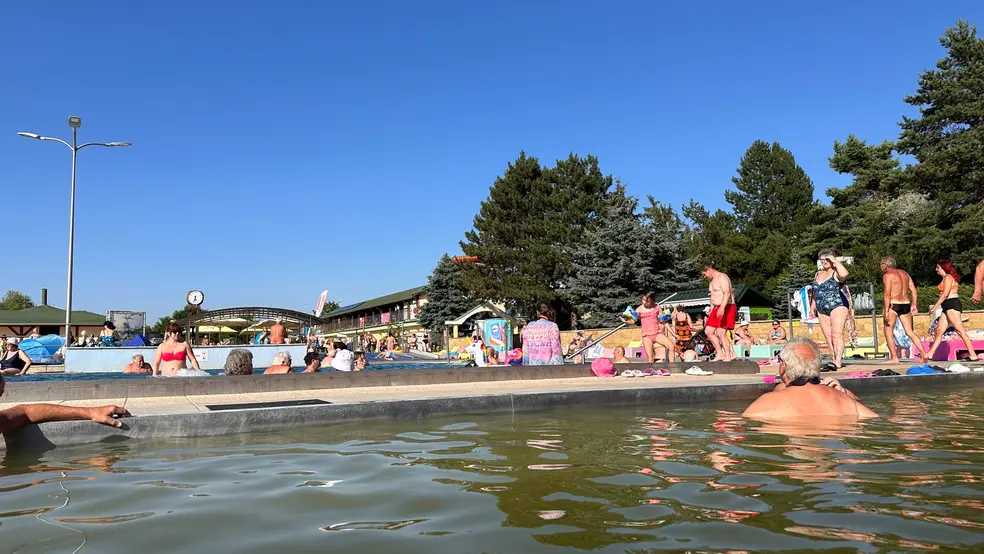 Lidé odpočívají v minerálním bazénu v Podhájske s typicky hnědavou vodou