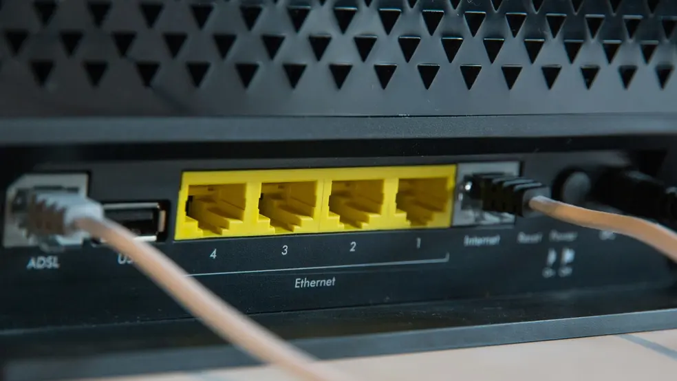 Detailní záběr na zadní stranu internetového modemu s ethernetovými porty a připojenými kabely