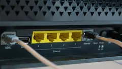 Detailní záběr na zadní stranu internetového modemu s ethernetovými porty a připojenými kabely