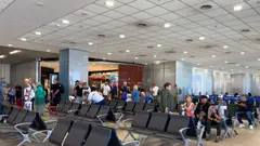 Lidé se zavazadly čekají v hale letiště