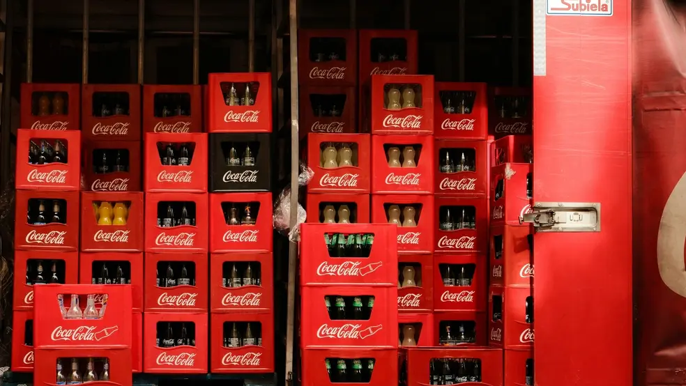 Regály plné lahví Coca-Cola v přepravkách ve skladu