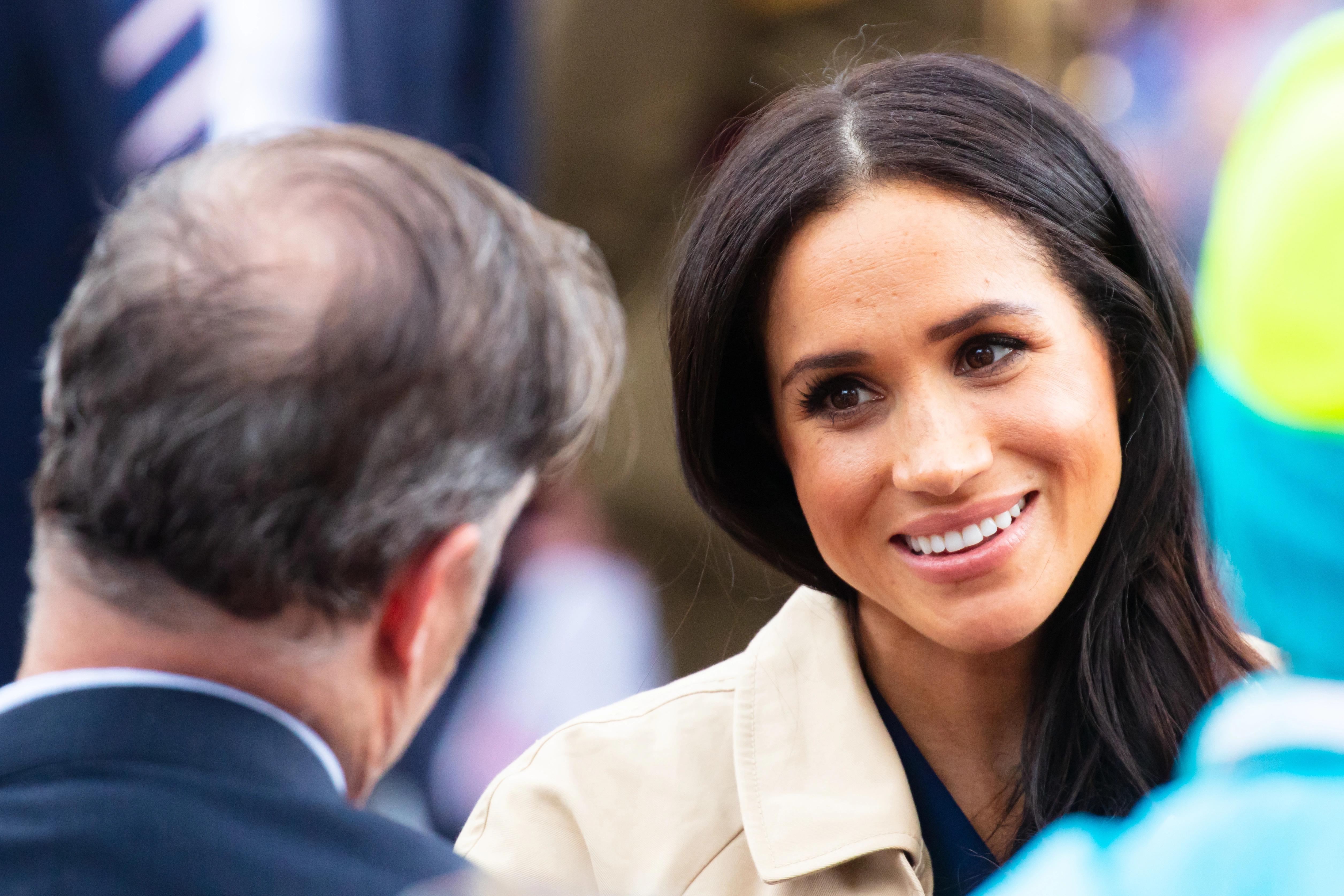 Detailní záběr na Meghan Markle, jak se usmívá při rozhovoru