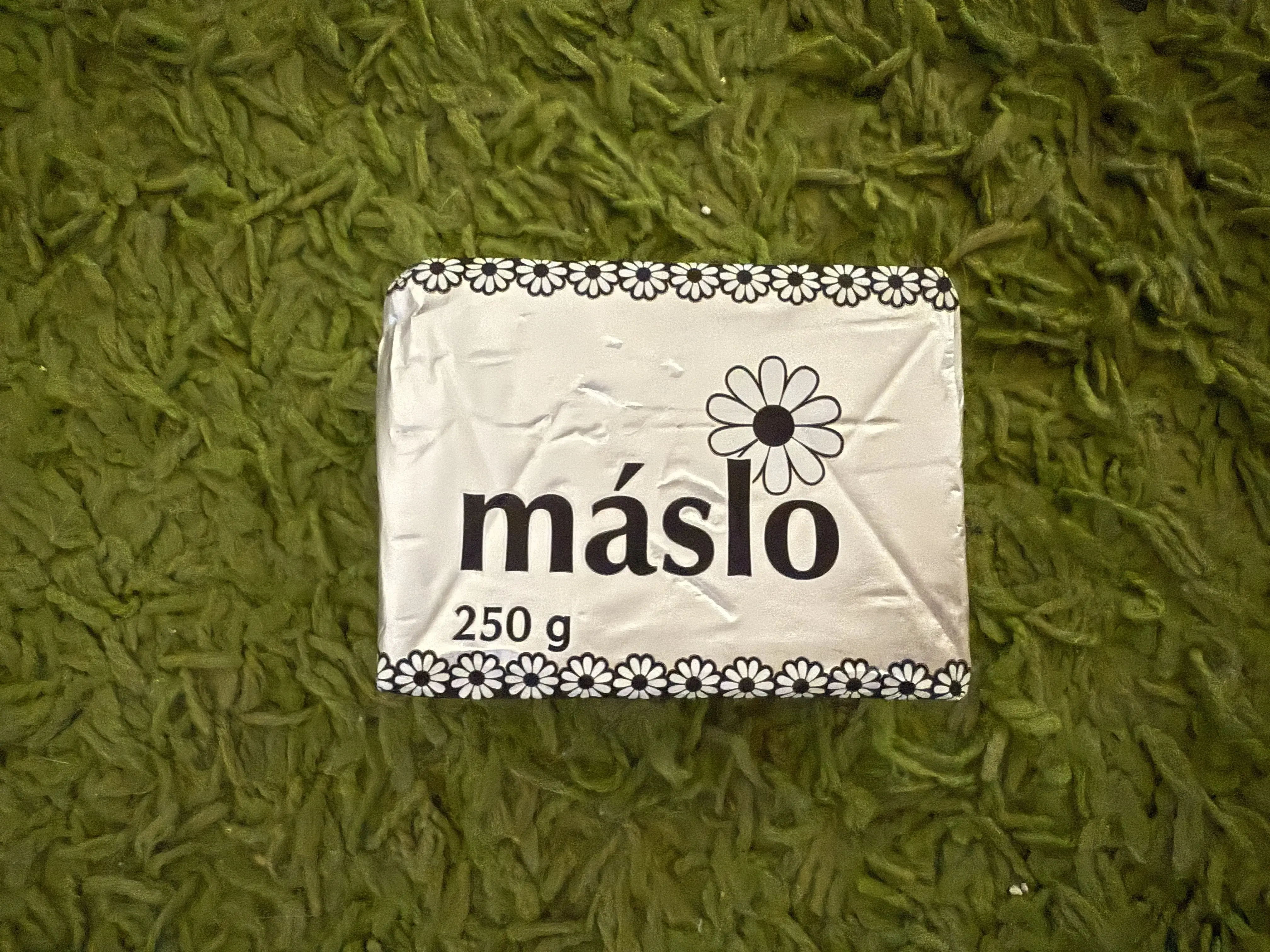 Otevřený balíček másla s viditelnou texturou