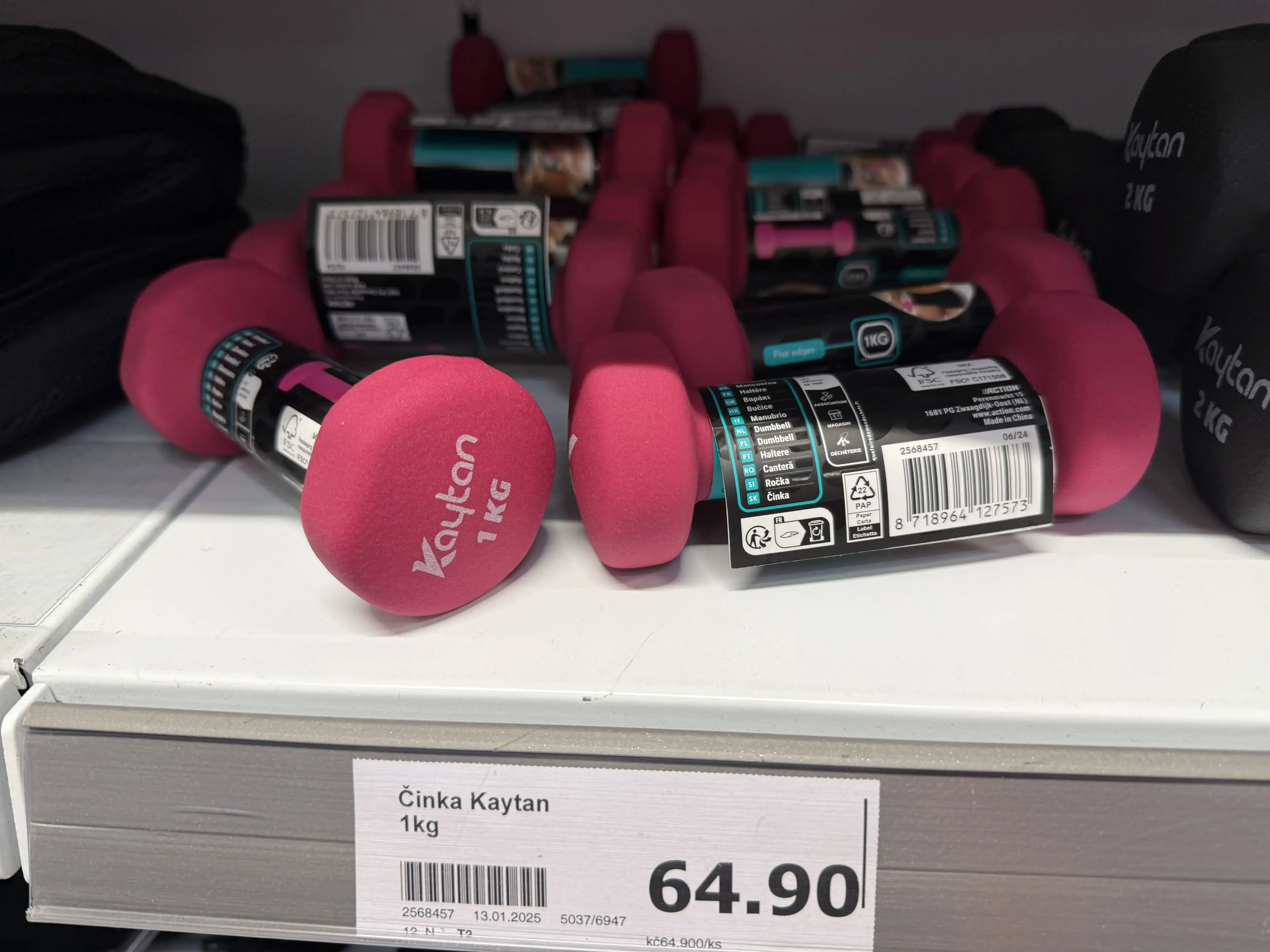 Činky různých hmotností vyskládané na regálu