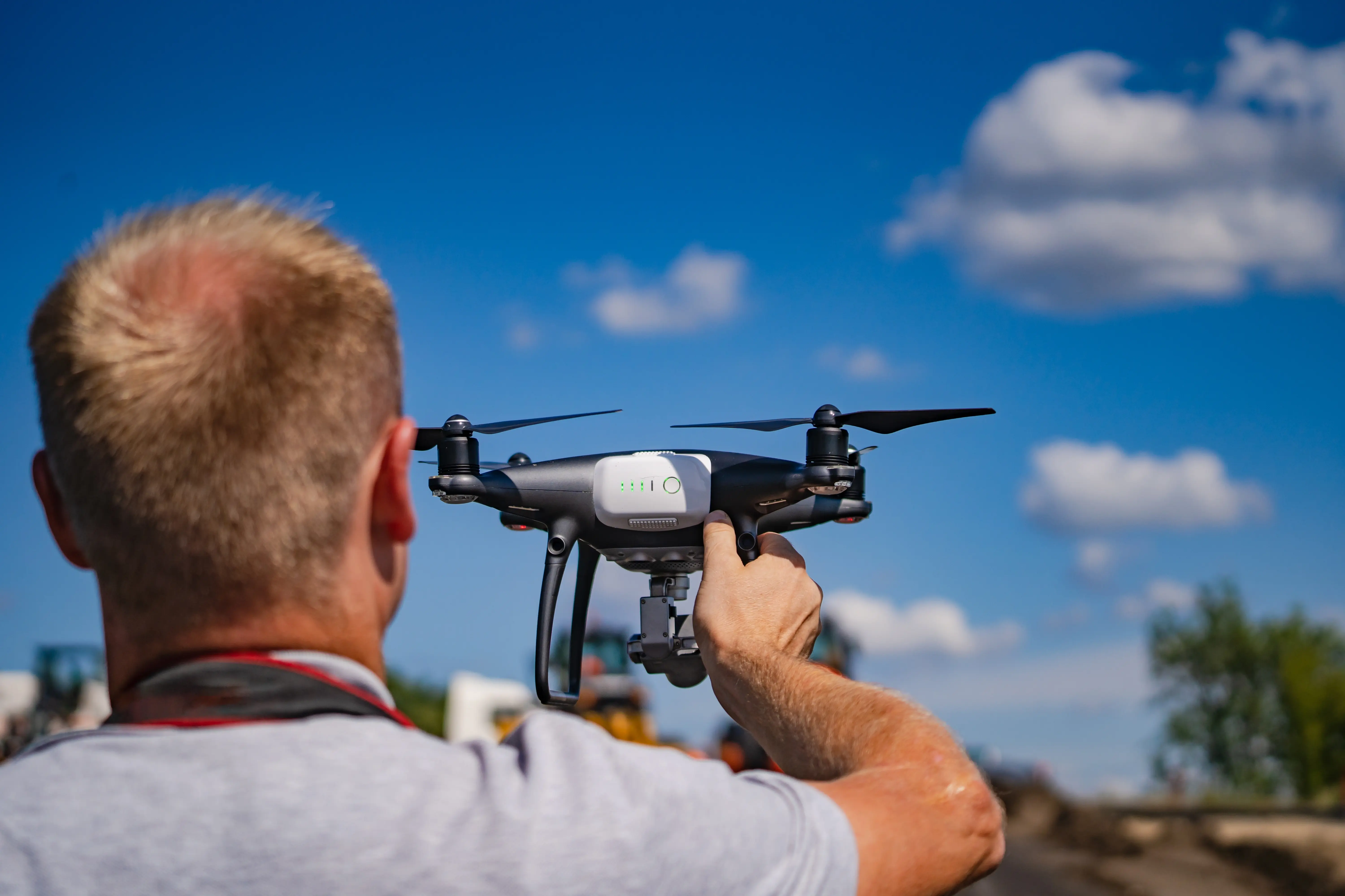 Technik v reflexní vestě s tabletem a dronem před solárními panely.