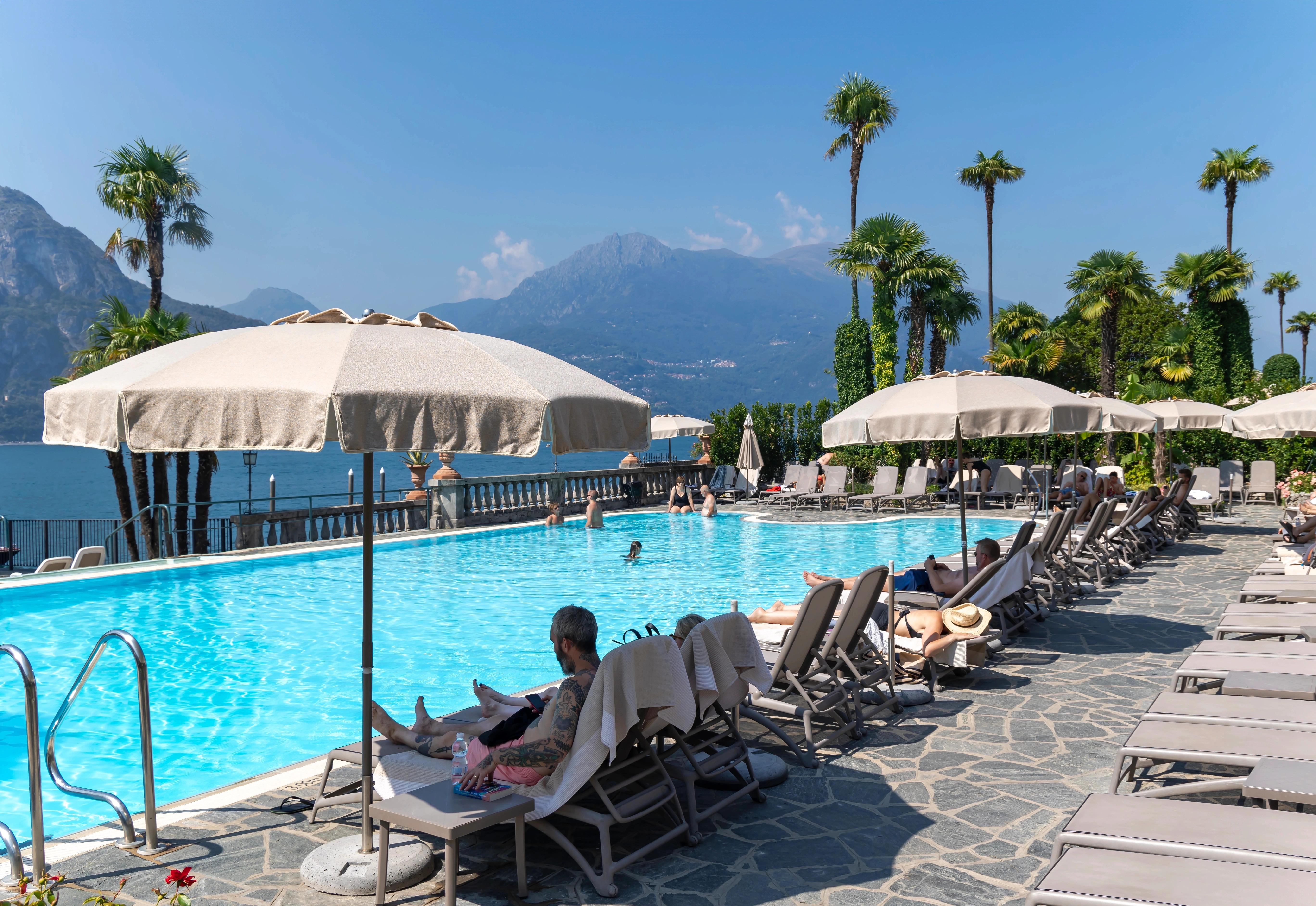 Slunečný den u hotelového bazénu s lehátky a palmami