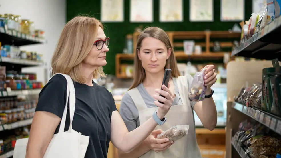 Prodavačka v obchodě mluví se zákazníkem u regálu