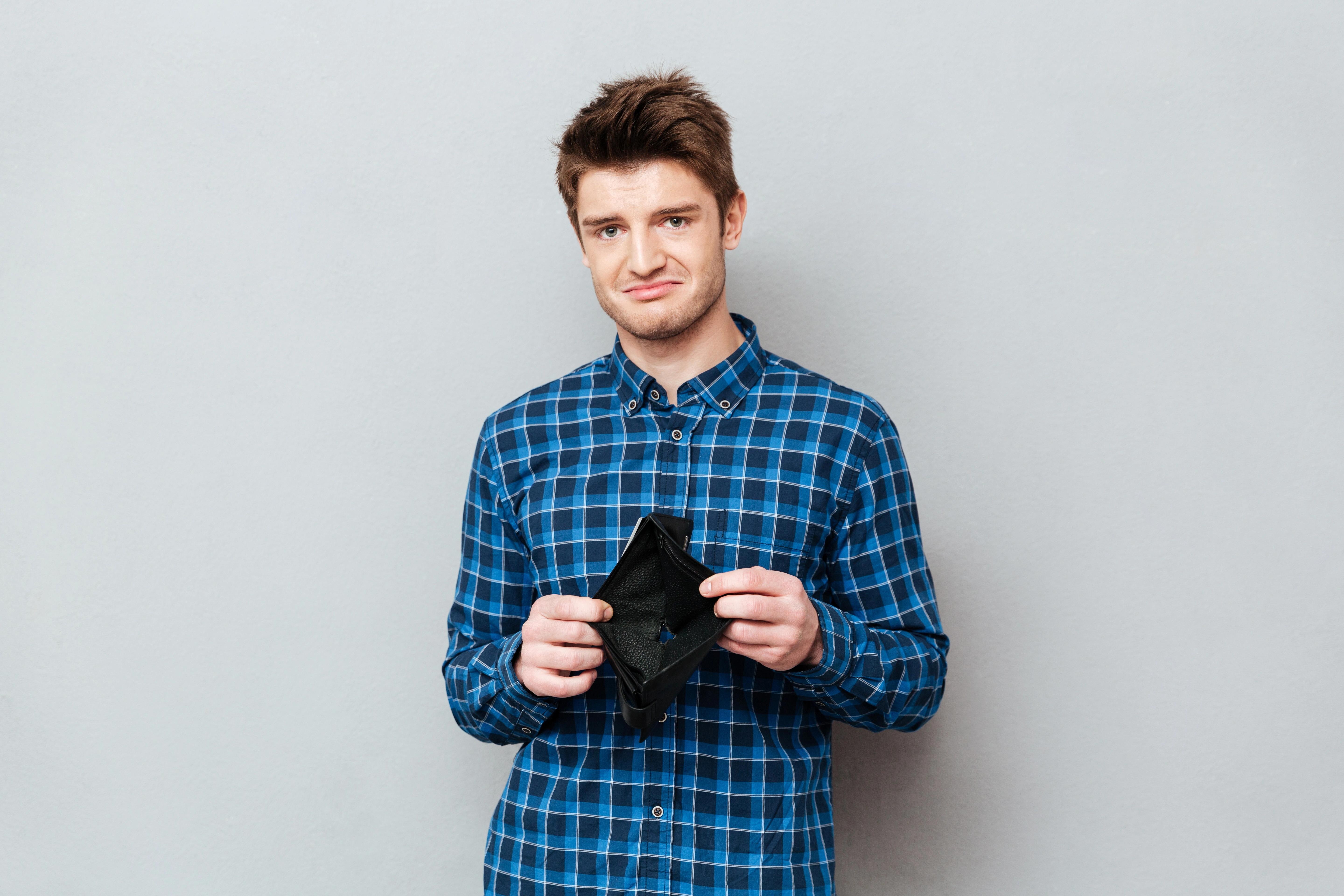 Muž počítající rodinný rozpočet u kuchyňského stolu