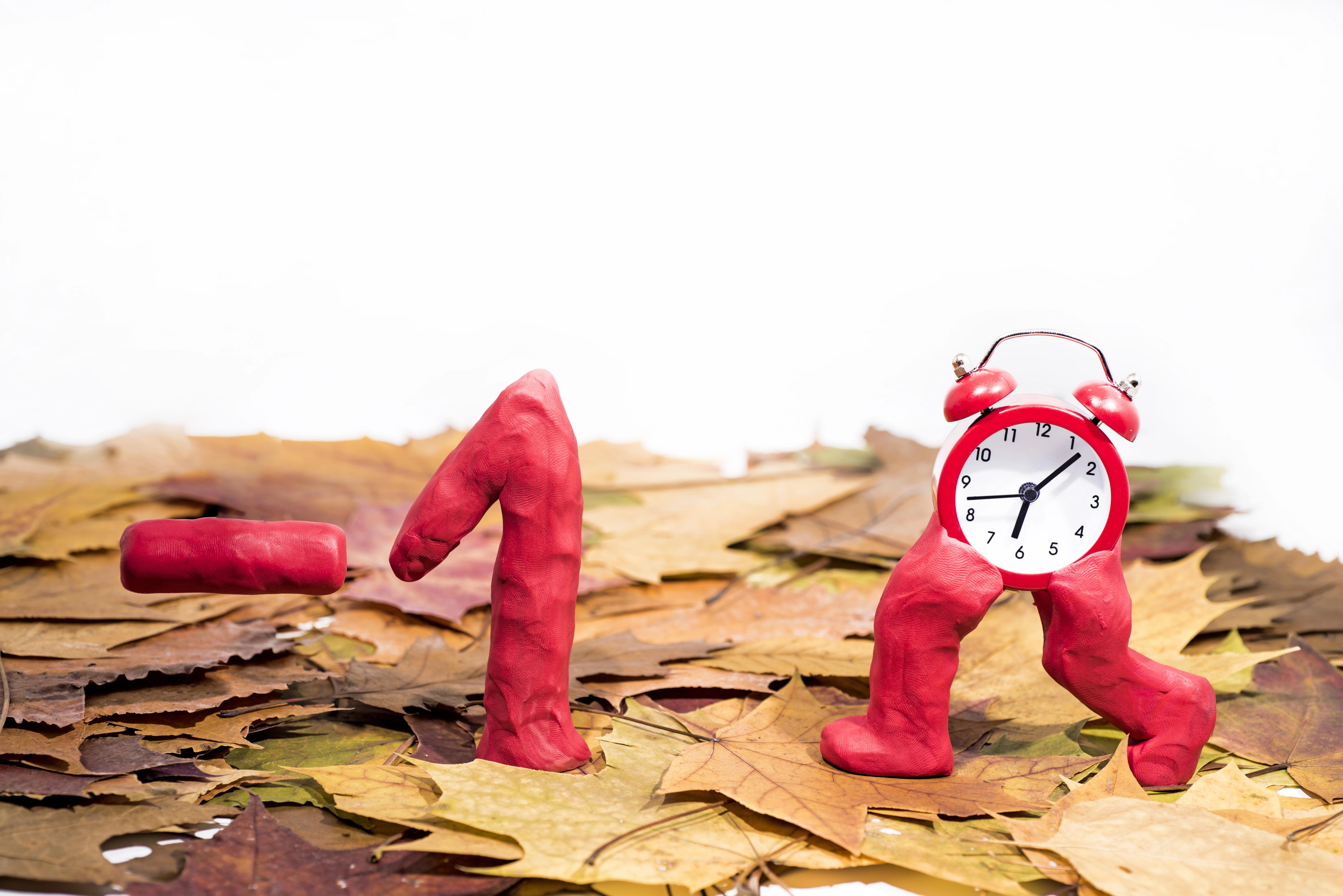 Budík ukazující dvě různé časy vedle okna s ranním sluncem