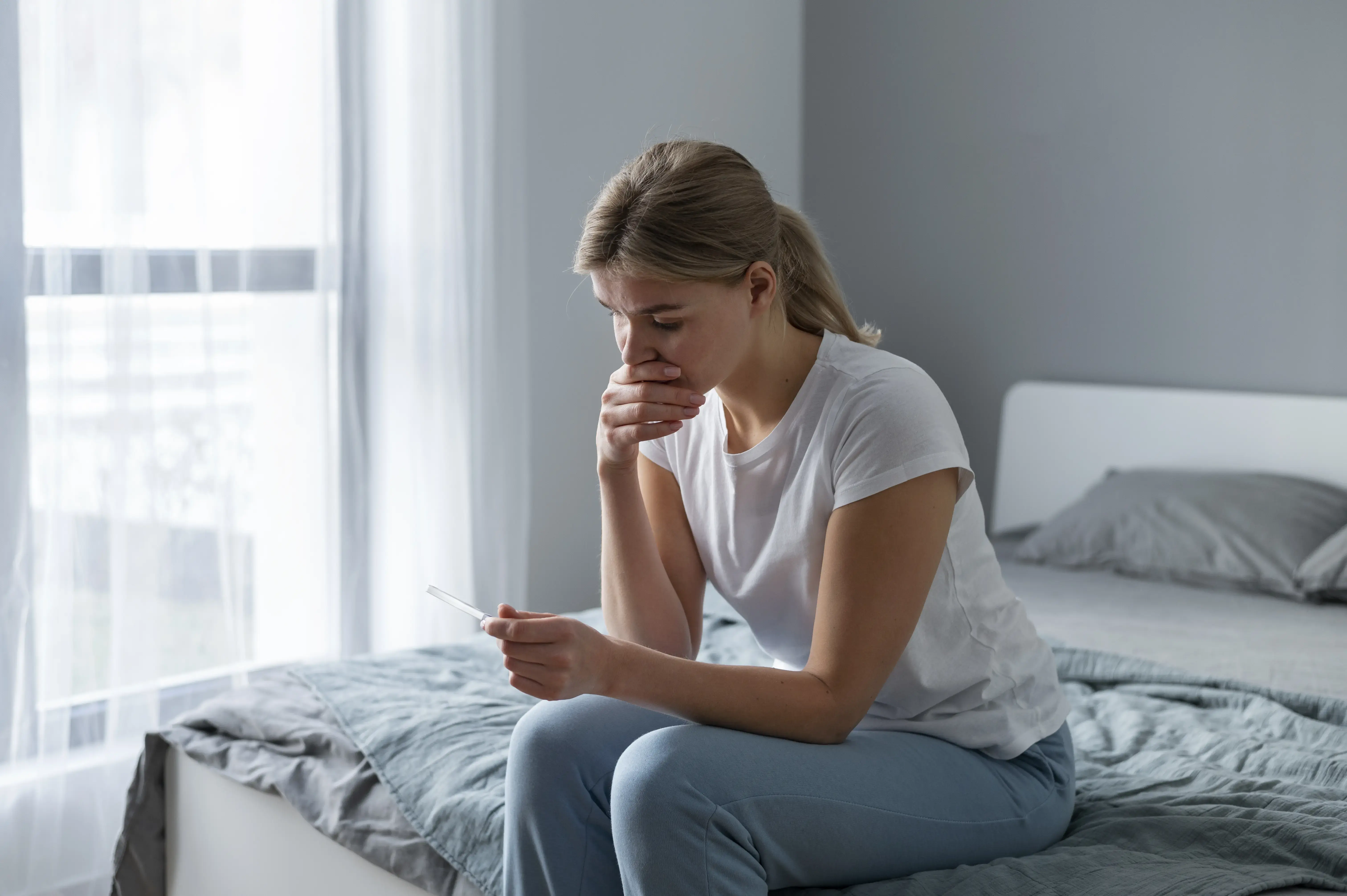 Žena se zasněným pohledem držící hrnek v rukou