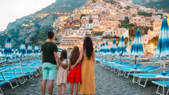 Rodiče s dětmi stojí na pobřeží a obdivují výhled na město v Itálii