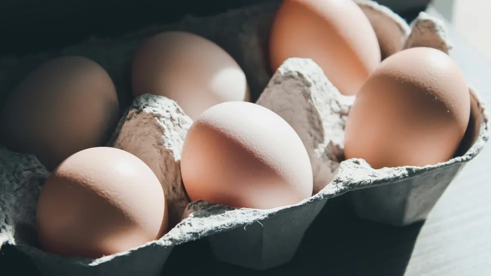 Několik čerstvých vajec uložených v kartonové krabici na stole