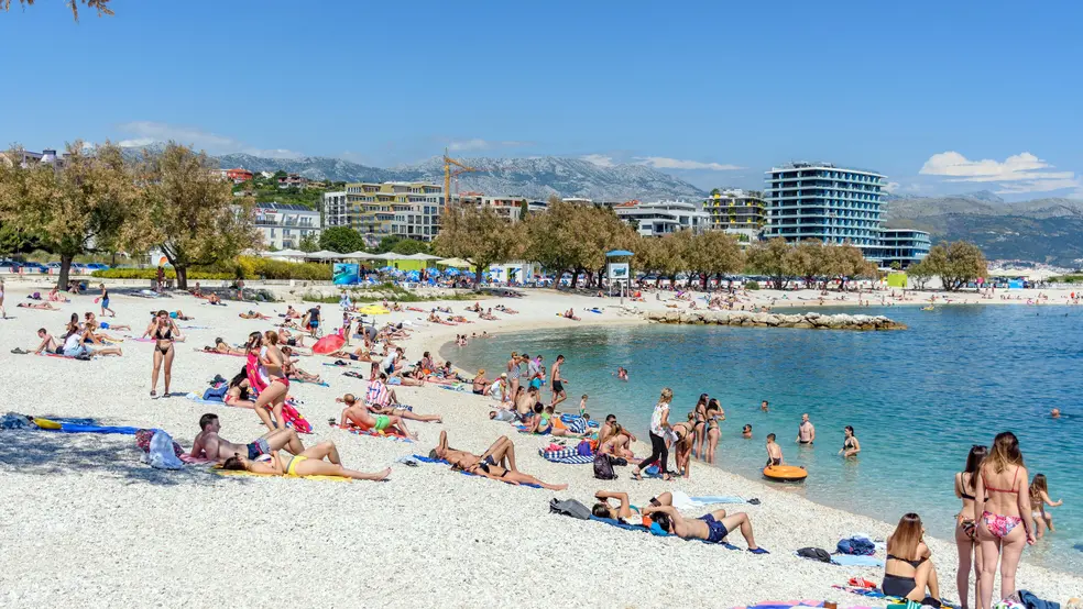 Davy lidí relaxujících a koupajících se na pláži v chorvatském Splitu