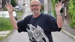 Zdeněk Pohlreich v tričku s orlem během rozhovoru, v pozadí motorky