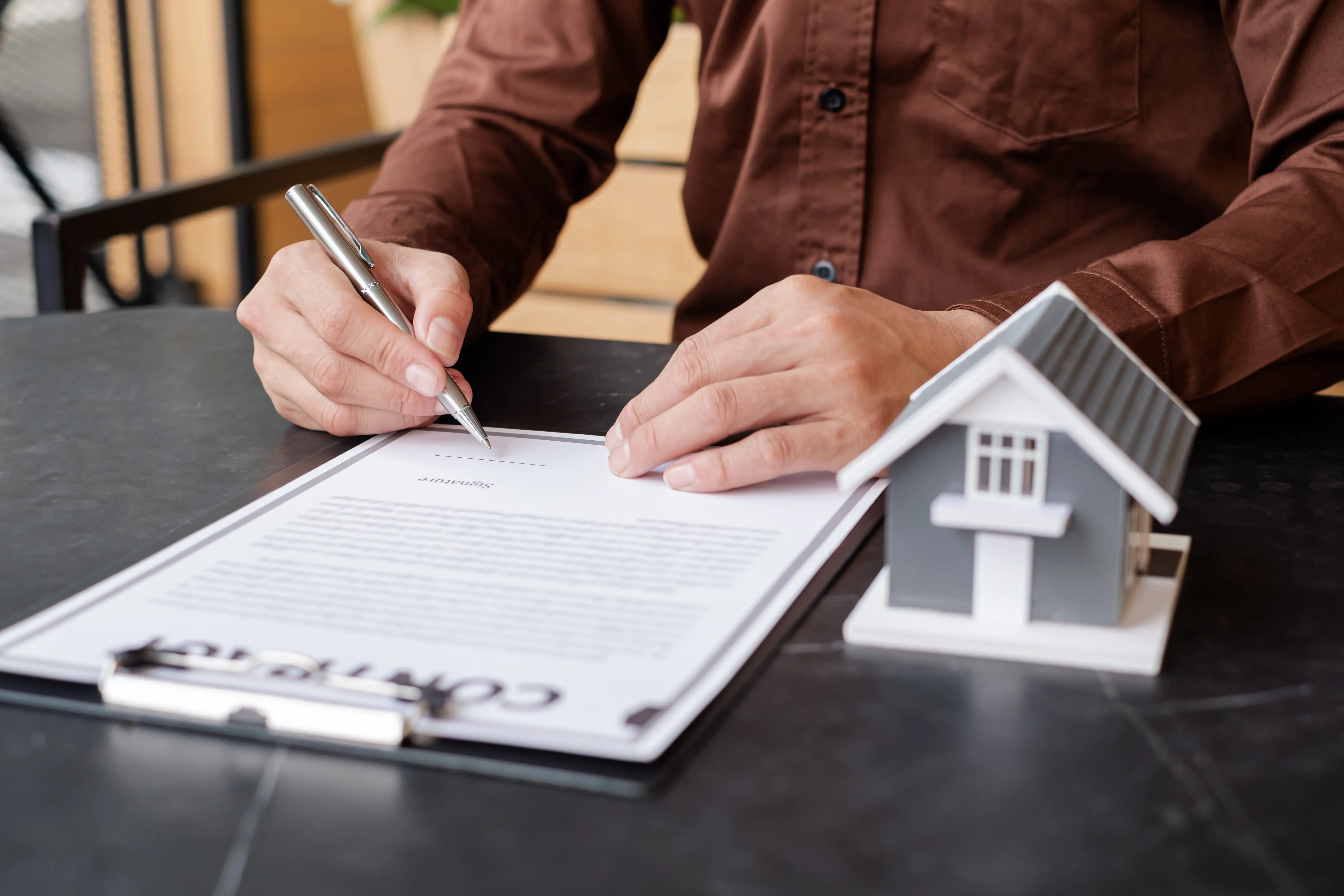 Ruka podepisující podnájemní smlouvu na stole