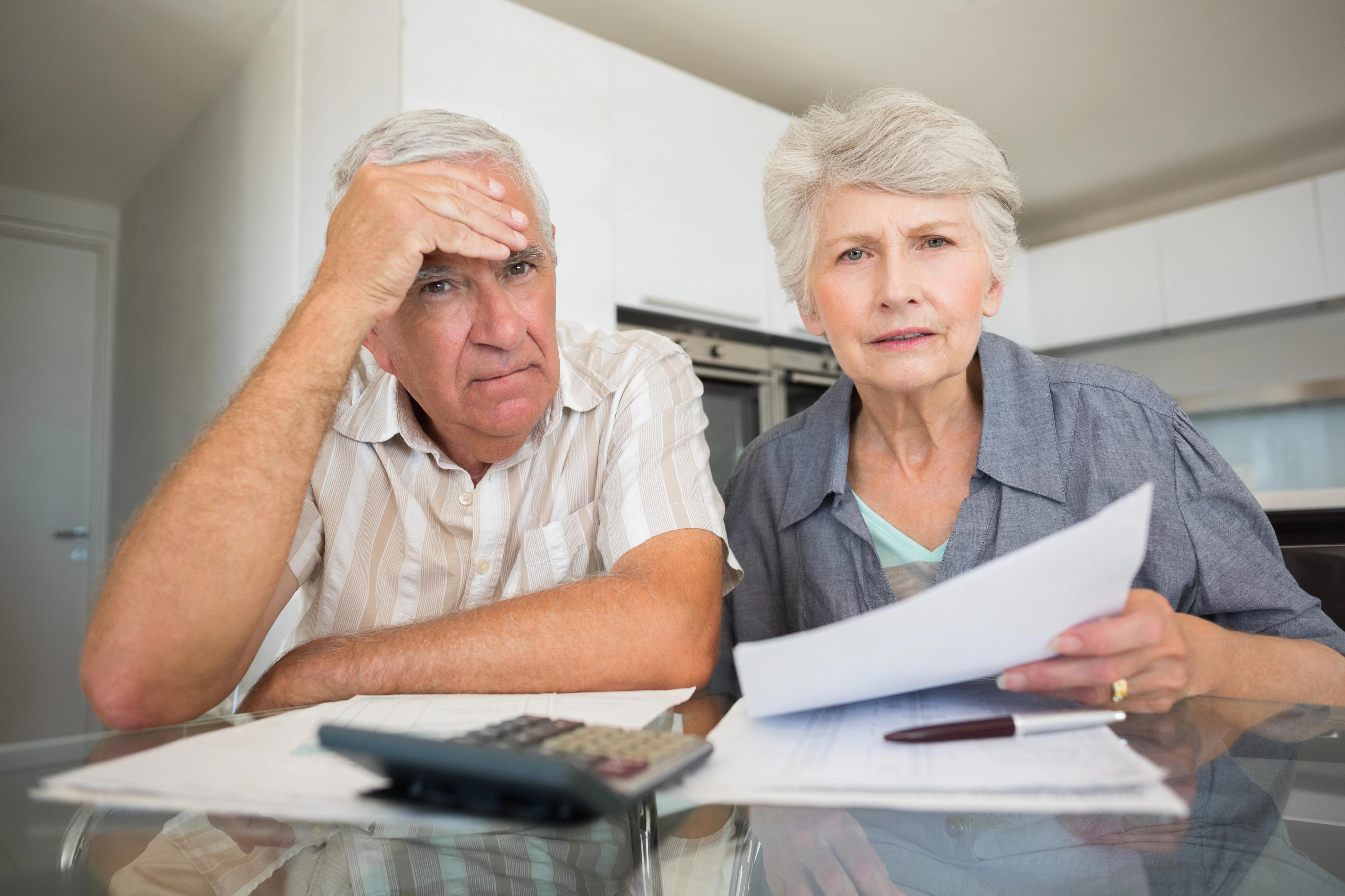 Důchodci sedí u stolu a zkoumají složky s dokumenty