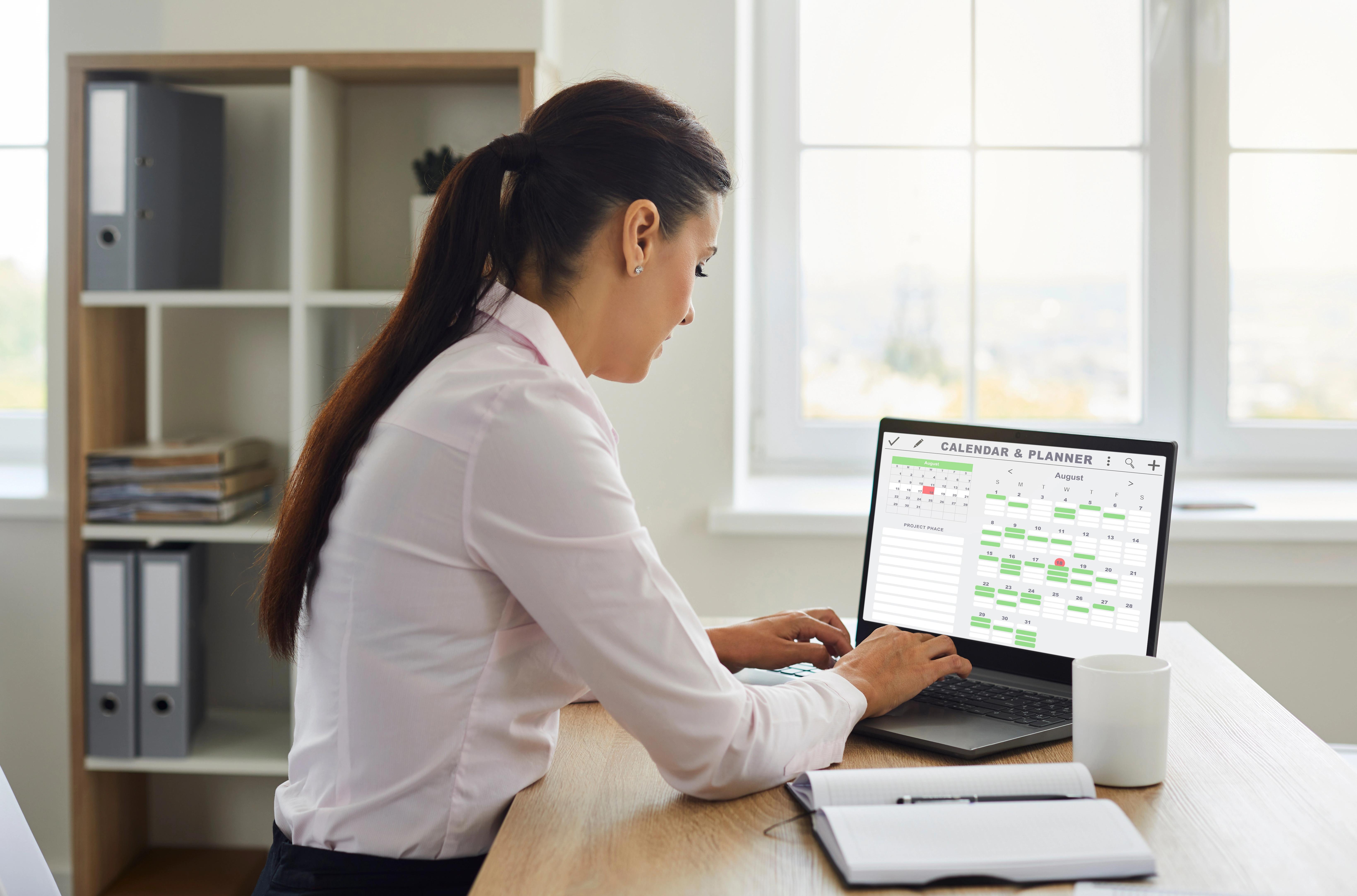 Mladá žena sedí u stolu s notebookem a pracuje na projektu