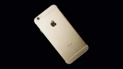 Zadní strana zlatého iPhonu položená na černém pozadí