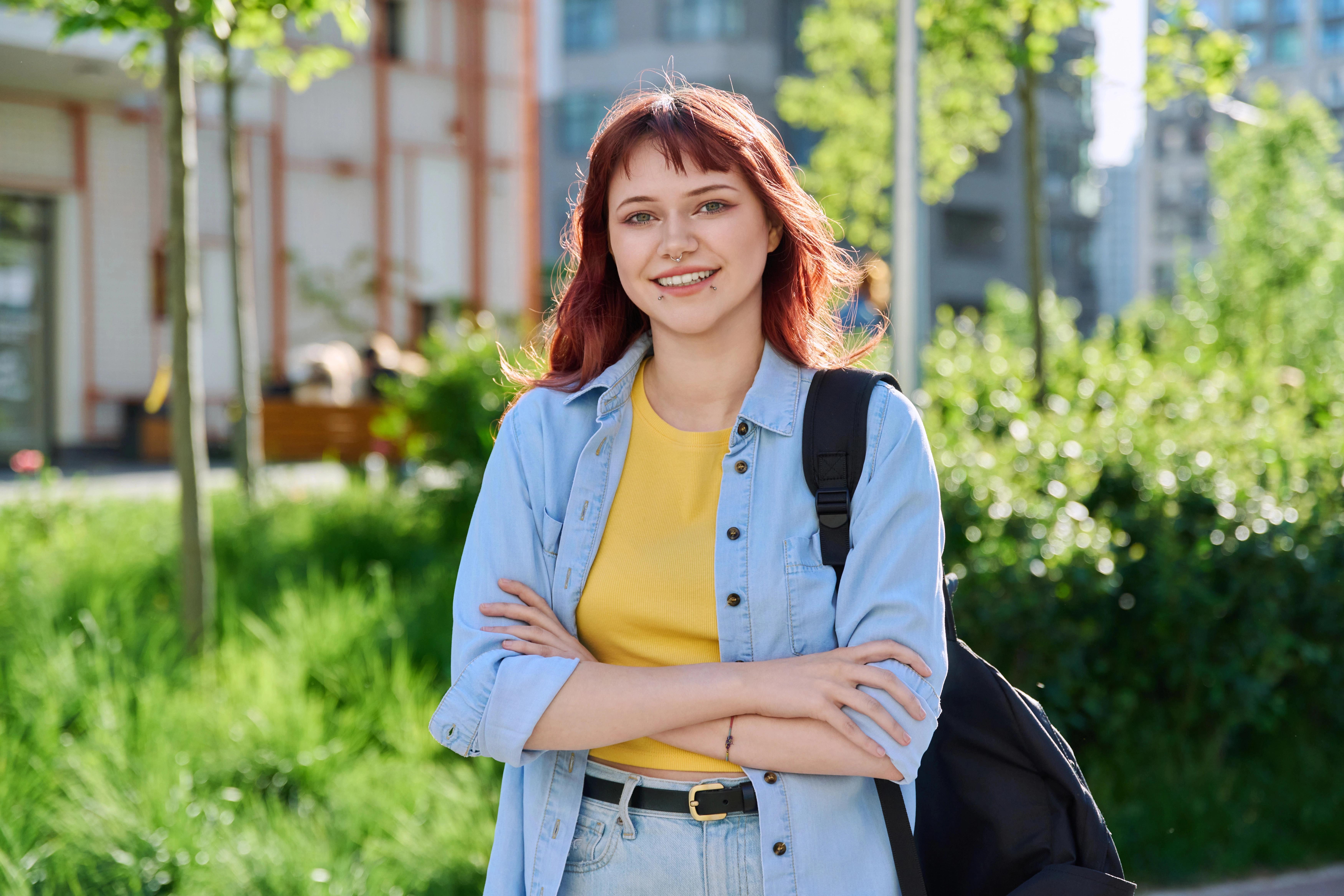 Mladá žena drží tašku s potravinami a usmívá se před obchodem