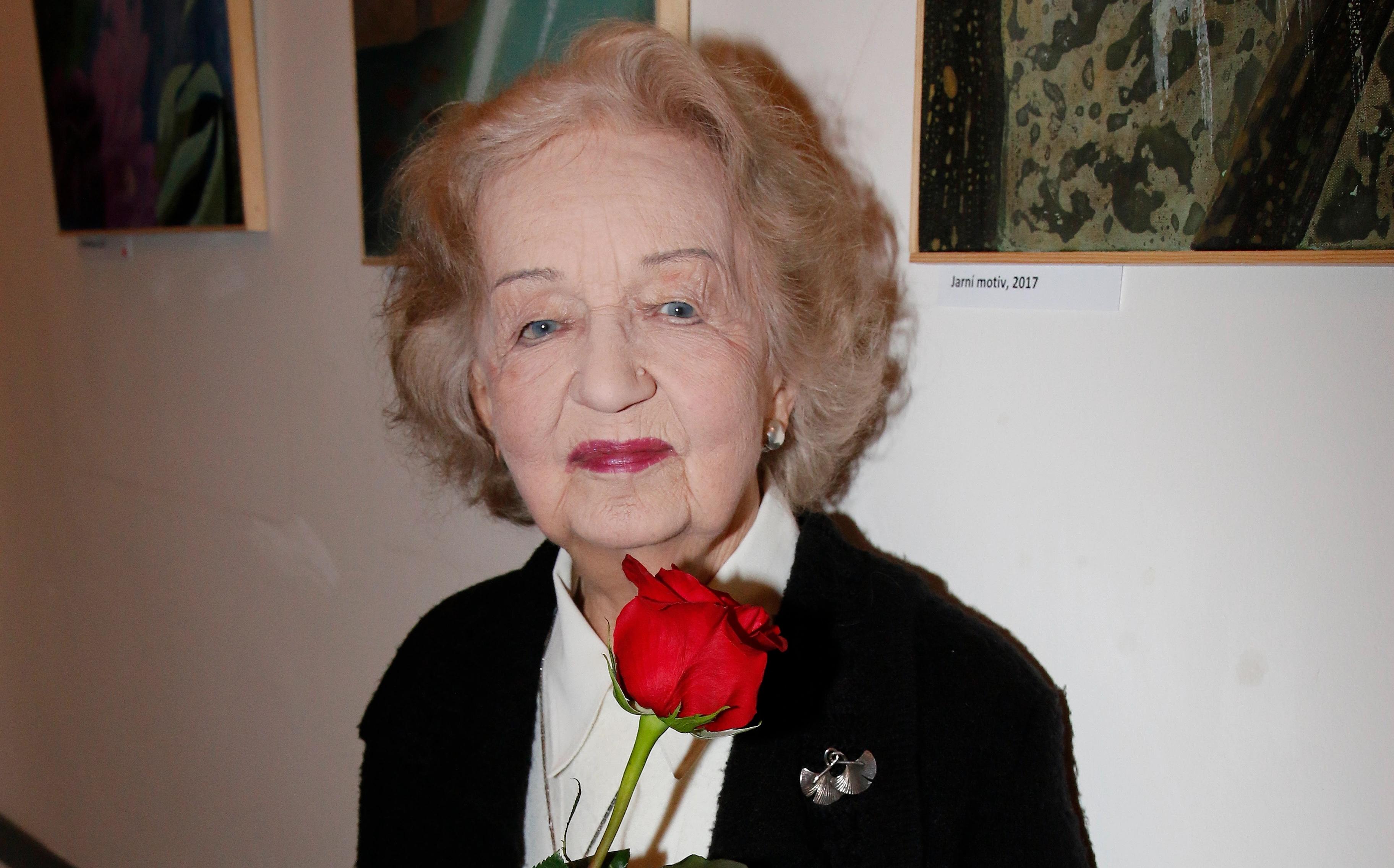 Blanka Bohdanová stojí vedle židle s květinami