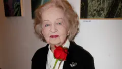Blanka Bohdanová stojí vedle židle s květinami