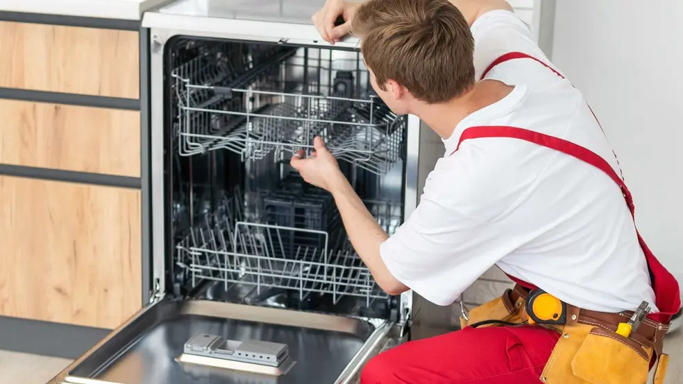 Technik kontroluje a opravuje myčku na nádobí v kuchyni