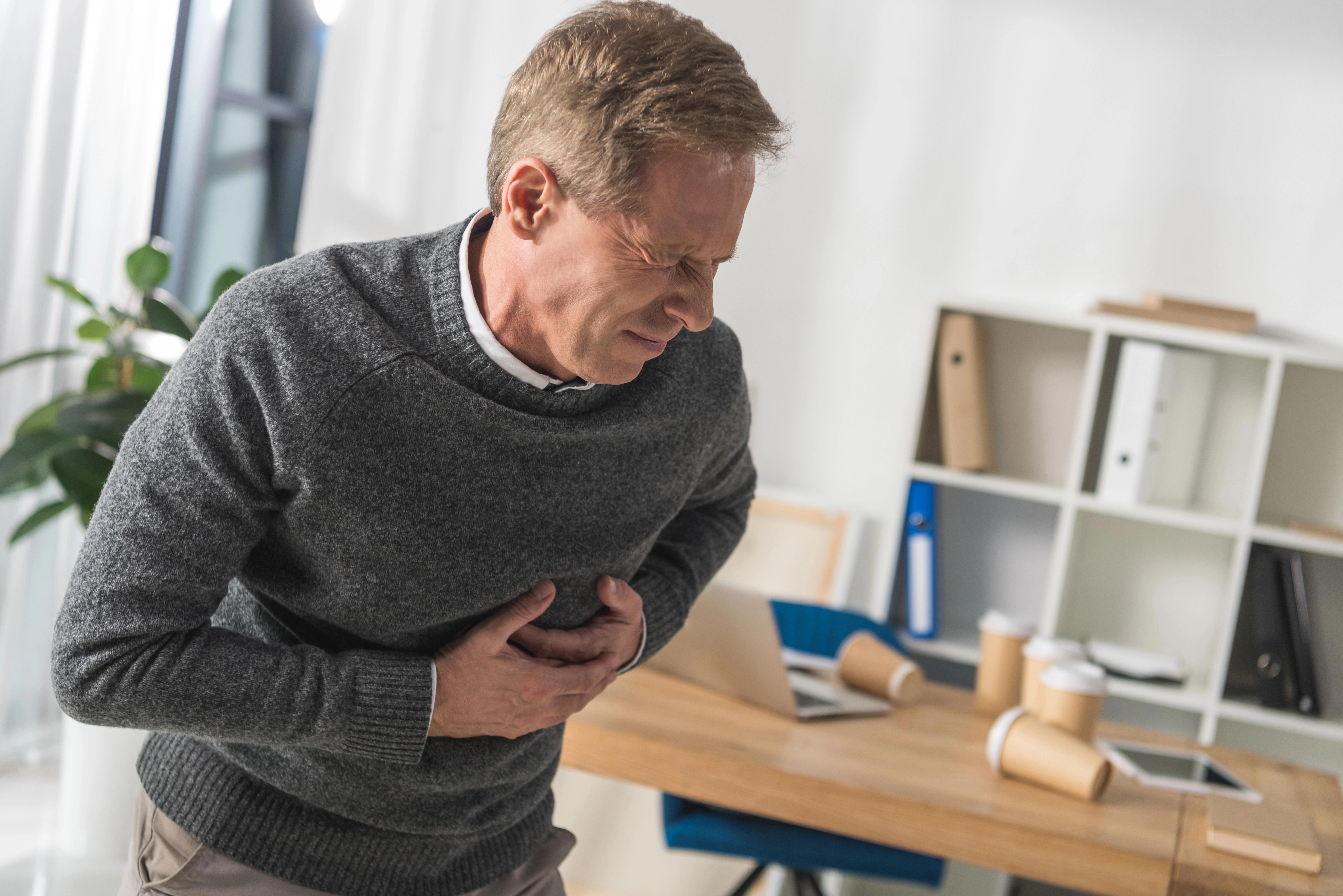 Muž si drží břicho a tváří se bolestivě