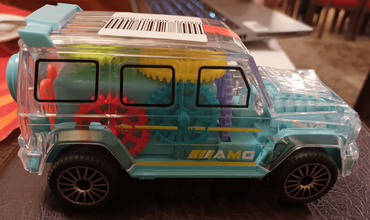 Plastová hračka ve tvaru auta s viditelnými barevnými převody a ozubenými koly