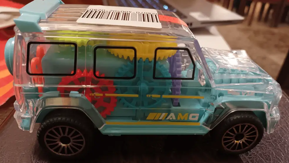 Plastová hračka ve tvaru auta s viditelnými barevnými převody a ozubenými koly