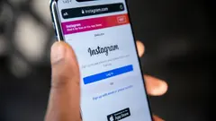 Mobilní telefon s otevřenou přihlašovací stránkou Instagramu na prohlížeči Safari.