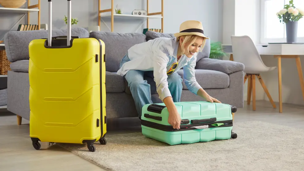 Usměvavá žena si nanáší opalovací krém na tvář, v pozadí pláž a moře