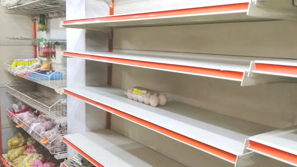 Prázdné police v potravinách, na jedné z nich leží poslední balení vajec
