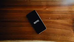 Černý telefon na dřevěném stole s nápisem "INSPIRE"