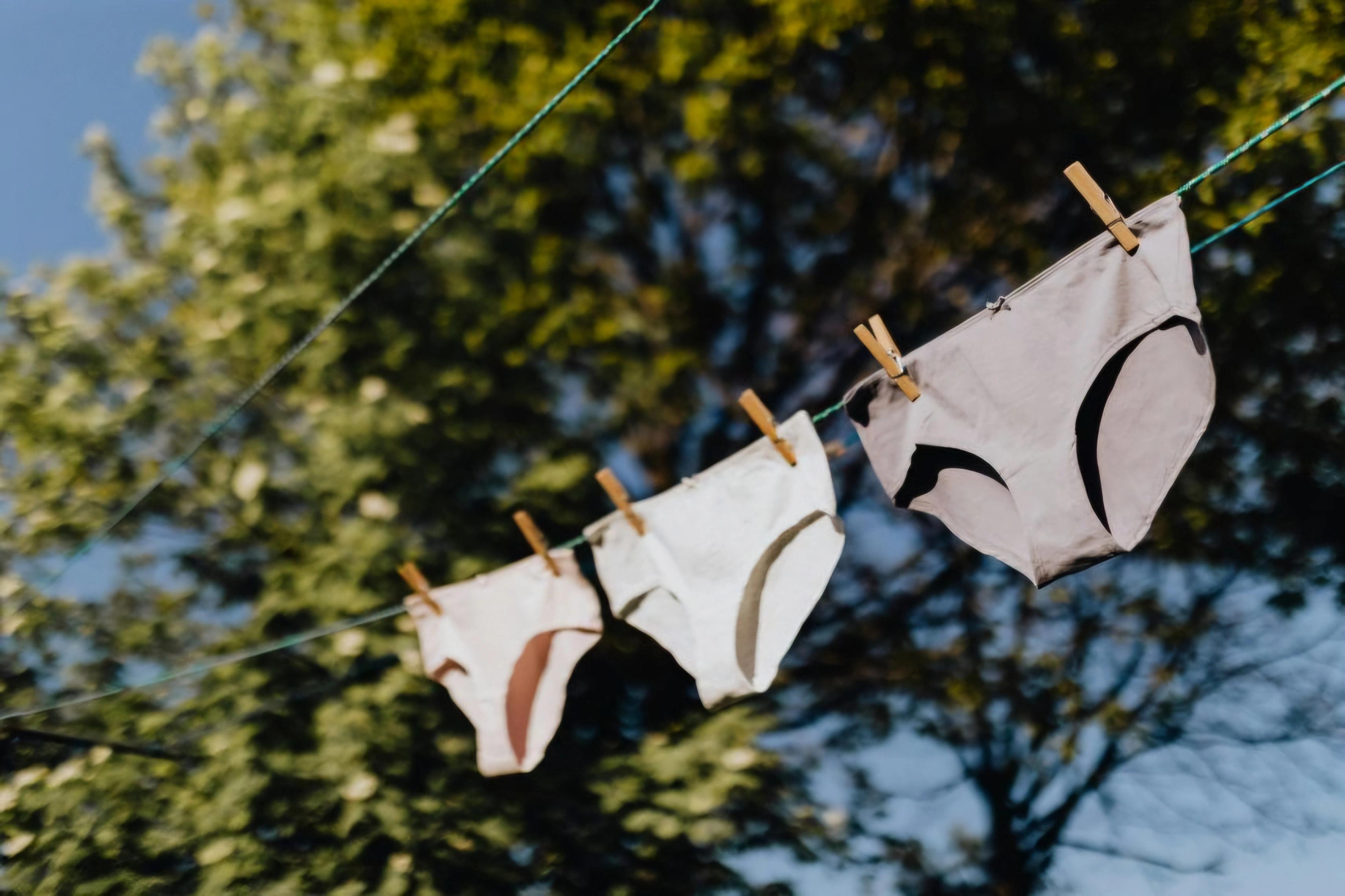 Barevné spodní prádlo rozložené na stole s varovným symbolem