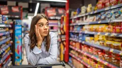Žena zkoumá produkty a kontroluje složení potravin v regálu obchodního řetězce.