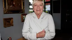 Usměvavá Jaroslava Obermaierová v béžovém kabátku před obrazy